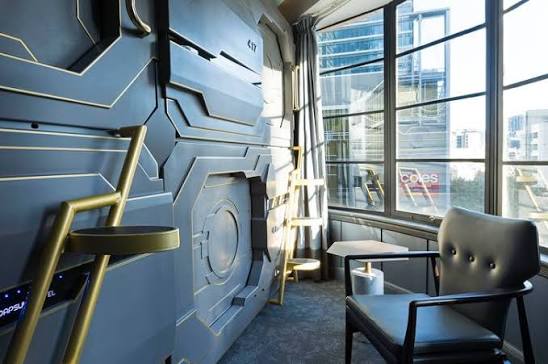 A corridor of enclosed sleeping capsules stacked along a wall, lit from inside each cabin.