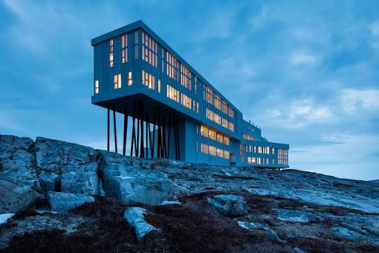 Fogo Island Inn, a long white building raised on wooden stilts on bare rock at the edge of the Atlantic.