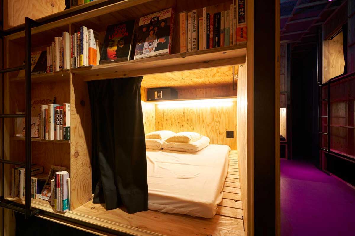 Sleeping berths cut into floor-to-ceiling plywood bookshelves at Book and Bed Tokyo.