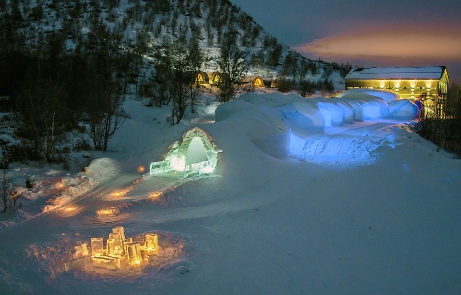 An ice-carved corridor at Kirkenes Snowhotel in northern Norway, lit from within the snow walls.